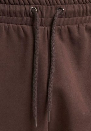 Bruine sweatpants hebben een elastische tailleband met een koord. De stof is glad met een licht gestructureerde afwerking.