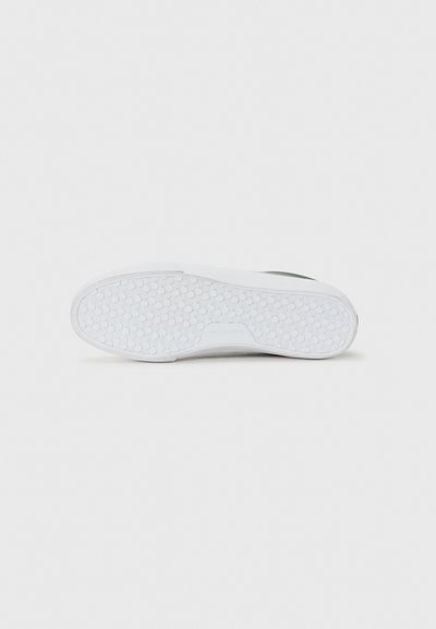 White sneaker sole with circular grip patterns, flat design, and subtle brand text in the center on a plain light background.