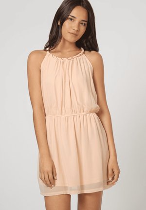 Vestido sin mangas de color durazno con un escote fruncido, cintura ceñida y falda fluida. Hecho de una tela ligera y translúcida.