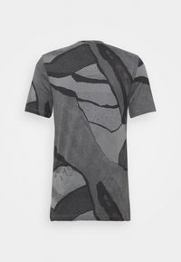 Camiseta de manga corta en gris oscuro con patrones abstractos en negro, que presenta un escote redondo y una textura suave y lisa.