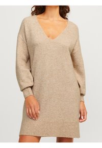 Kerman neulemekko, jossa on syvä V-pääntie, rento hihansuu ja ribbireunus. Pehmeä kangas, keskitason pituus.