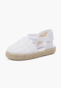 Scarpa in stile espadrillas bianca con tomaia texturizzata e cinghie incrociate in tessuto. Presenta una suola in juta naturale e un design con punta rotonda e piatta.