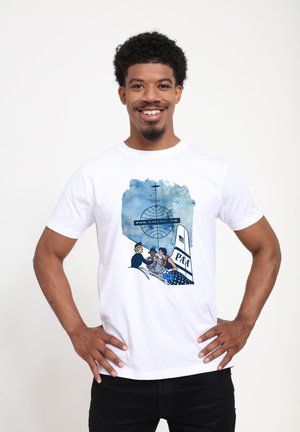 T-shirt en coton blanc avec un graphique bleu représentant un globe et des personnages autour d'un avion marqué « PAN AMERICAN » et « PAA ». 