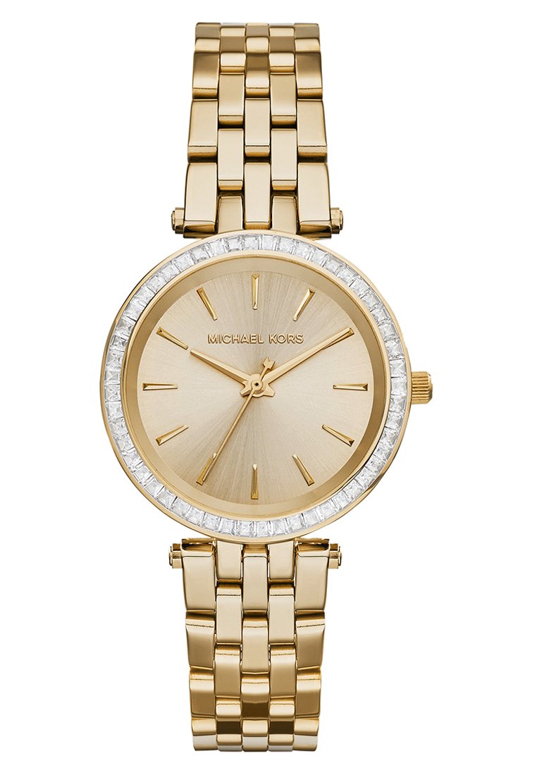 Orologio in metallo dorato con quadrante dorato spazzolato, lunetta decorata con cristalli e bracciale a maglie. Presenta indicatori delle ore minimalisti e una corona.