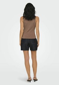 Brązowy prążkowany top bez rękawów zestawiony z ciemnymi dżinsowymi szortami, z lekko zaokrąglonym dołem. Zaprojektowany w dopasowanej sylwetce.