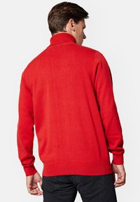 Czerwony sweter z wysokim kołnierzem, wykonany z teksturowanej dzianiny. Ma długie rękawy i dopasowany dół, pokazany z tyłu.