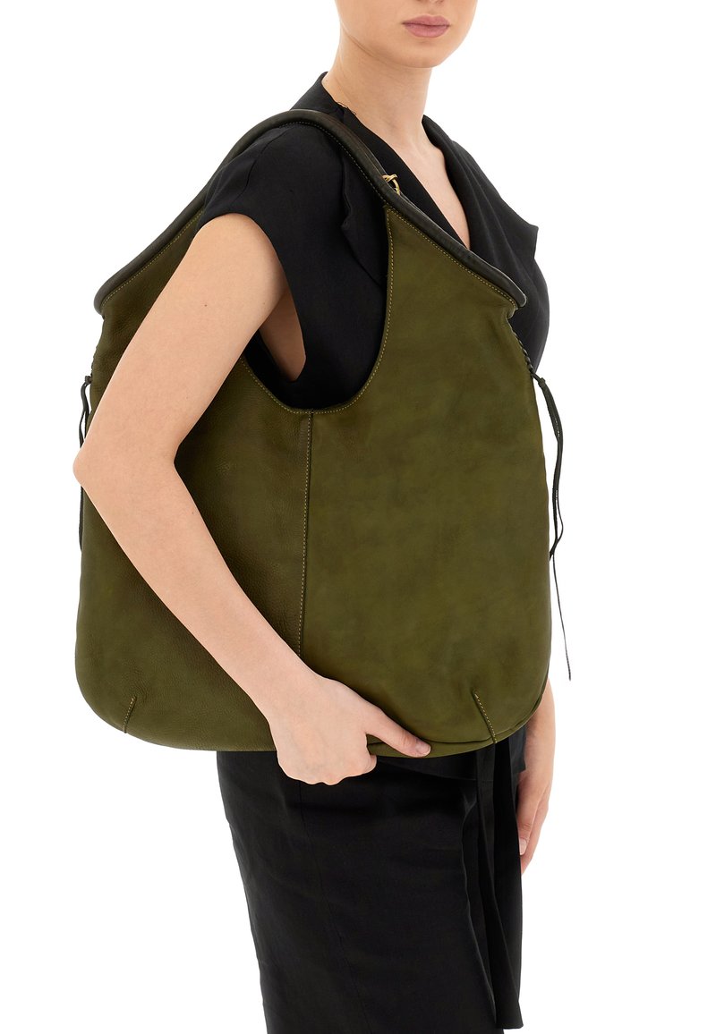 Borsa in pelle verde con una texture morbida, caratterizzata da una forma unica, ampia apertura e dettagli con coulisse regolabile. Indossata sulla spalla.