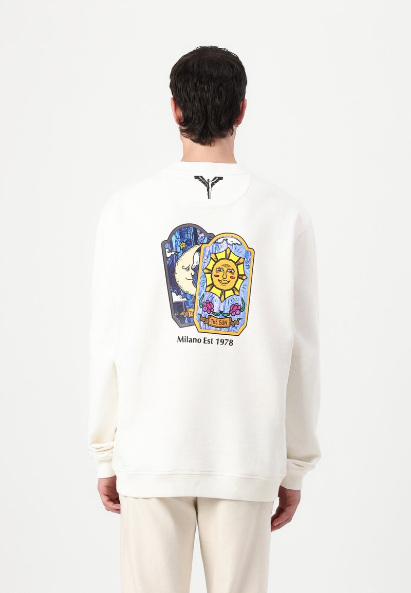 Hvit hettegenser med en fargerik grafisk design på baksiden, som viser en sol og måne med blomstrende detaljer, samt teksten "Milano Est 1978".