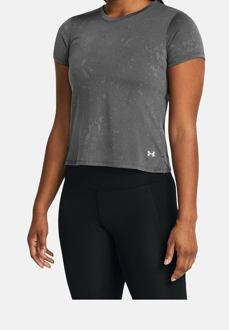 Šedé aktivní tričko s krátkým rukávem s texturovaným povrchem, které má kulatý výstřih a malé bílé logo na dolní levé straně.