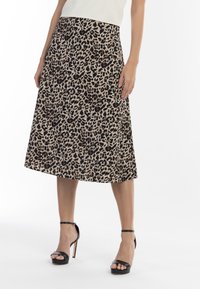 Leopardprint midi nederdel i tan og sort, glat tekstur, udstyret med en flair-design og en tætsiddende talje. Parret med sorte strop højhælede sko.