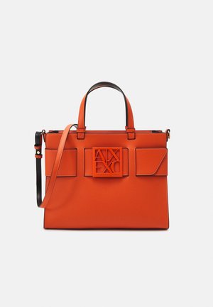 Sac à main synthétique orange avec poignées noires et bandoulière ajustable. Comprend une plaque de logo proéminente et deux poches avant. Texture lisse.