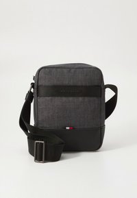 Szürke szövetoldaltáska fekete bőr díszítésekkel, állítható pánttal, logós szalaggal és alul kis piros-fehér részlettel.