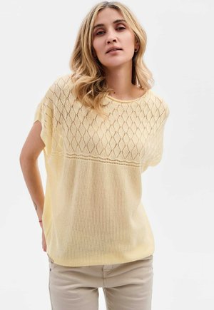 Pull en tricot léger jaune pâle avec un motif en diamant, manches courtes larges et coupe ample et texturée. Tissu doux et col rond.