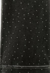 Tissu noir avec une texture veloutée ornée de petits embellissements métalliques argentés disséminés. Ourlet soigneusement cousu en bas.