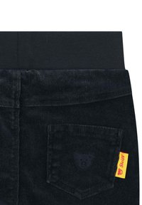 Černé kalhoty z kordu s elastickým pasem, obsahující zadní kapsu s emblémem medvěda a žlutou a červenou nášivkou.