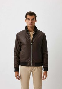 Bruine leren jas met een ritssluiting, geribbelde manchetten en kraag, met een gladde textuur en een slim fit ontwerp. Draagt over een beige top.