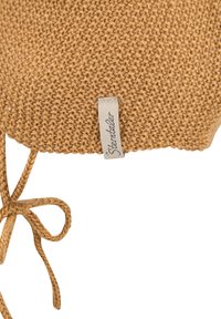 Knit cap in mustard color, featuring a textured pattern and a drawstring tie. Includes a small fabric tag with brand name.