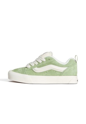 Low-top sneaker with light green suede upper, white wave stripe, thick white sole, and white laces, shown in side profile.