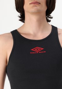 Black ribbed tank top with a round neckline, featuring a red "BOILER ROOM" logo at the center. Smooth texture, form-fitting design.