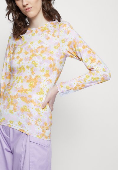 Camisola de mangas longas em cores pastéis com um padrão floral de flores laranja, amarelas e roxas. Tecido suave com um corte justo.