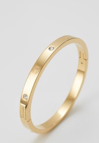 Bracelet en jonc plaqué or avec deux accents en cristal transparent, texture lisse et détail de logo gravé, doté d'un design de fermoir sécurisé.