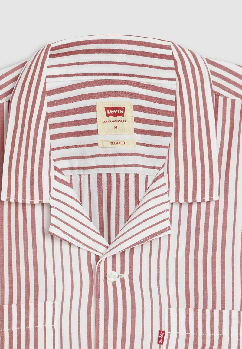 Camisa de rayas rojas y blancas con un collar relajado, bolsillo frontal y etiqueta de marca Levi's en el interior del cuello. Material de algodón.
