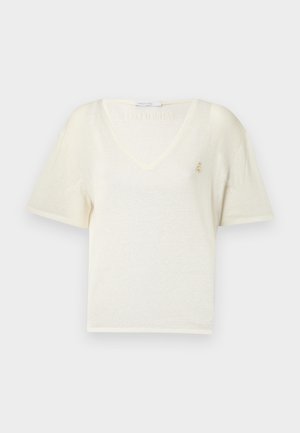 Short-sleeve, V-neck t-shirt in soft cream fabric with a relaxed fit, featuring a small gold emblem on the chest. Smooth texture.
