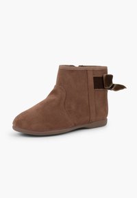 Braune Wildleder-Stiefeletten mit runder Spitze, elastischem Seitenpanel und einem samtigen Schleifenakzent auf der Rückseite. Flache Gummisohle für Komfort.