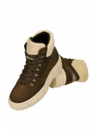 Bruine suède enkellaarzen met een crèmekleurige bontkraag, metalen veteroogjes en dikke witte rubberen zolen. Heeft een merkaccent op de hiel.