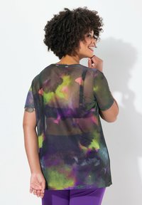 Gennemsigtig kortærmet top med et farverigt tie-dye mønster i lilla, grøn og sort. Casual design med en afslappet pasform og rund halsudskæring.