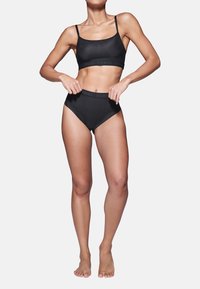 Set di bralette senza cuciture nera e slip a vita alta. Realizzato in materiale liscio, con vita elasticizzata e logo. Design minimalista.