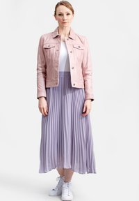 Roze leren jasje met frontzakken, witte t-shirt, en een vloeiende geplooide lavendelkleurige rok. Witte hoge sneakers.