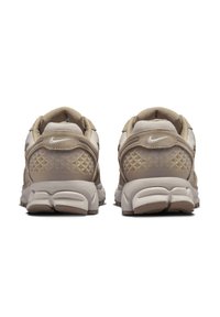 Nike sportcipő bézs árnyalatokban, melyek hálós és velúr anyagból készült, textúrázott sarokkal, gyémánt mintával, és párnázott fehér talppal rendelkeznek.