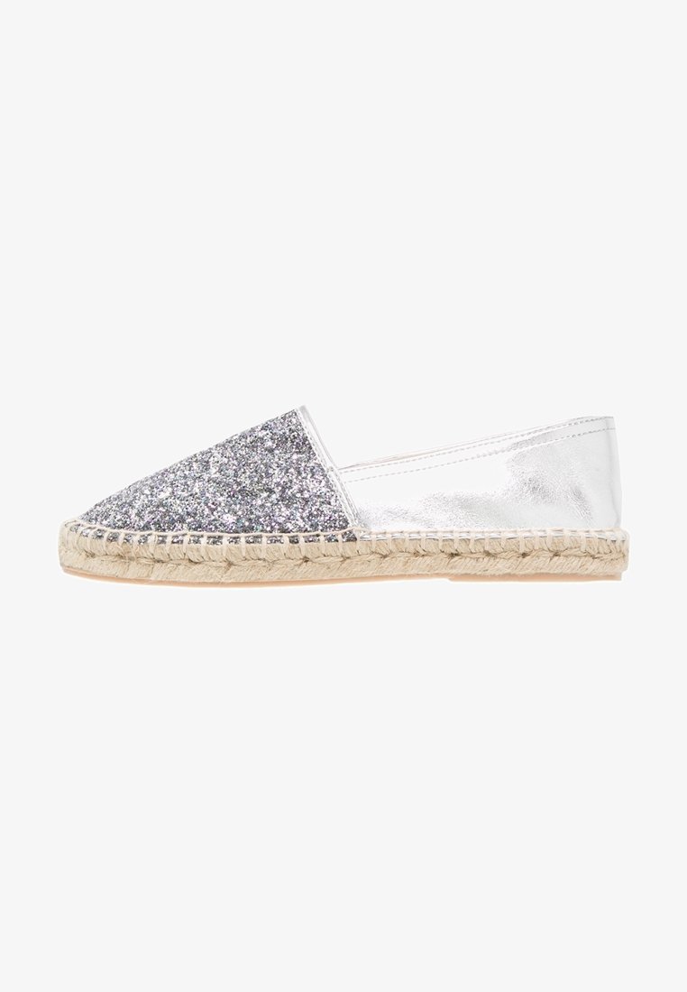 Espadrille argentée avec une tige pailletée et un côté métallique. Caractéristiques : semelle en jute tissée, bout rond et design plat.