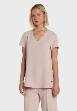 Lyhythihainen, vaaleanpunainen yläosa V-kaula-aukkolla, valmistettu sileästä kankaasta, jossa on hienovarainen kiilto ja kirjailtu logoyksityiskohta helmassa.