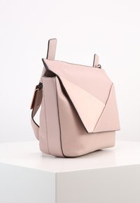 Borsa in pelle rosa con un design geometricamente flap. Ha una texture liscia, dettagli neri e una tracolla per il trasporto.