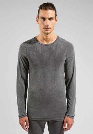 Graues Langarmshirt aus einem strukturierten, feuchtigkeitsableitenden Material. Verfügt über einen runden Ausschnitt und ein dezentes Muster auf der Brust.