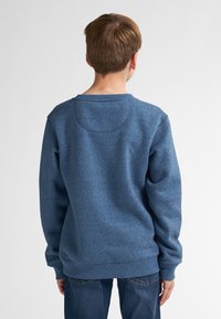 Sweatshirt en polaire bleu en tissu texturé, avec un col rond et des poignets côtelés, montré de dos avec un minimum de détails.