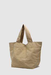 Beżowa torba na ramię o pomarszczonej fakturze, wyposażona w dwa szerokie uchwyty oraz dużą, otwartą komorę; minimalne szwy i brak widocznych okuć.