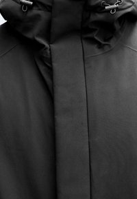 Czarna kurtka z kapturem o gładkiej fakturze, minimalistycznym designie i regulowanych troczkach przy szyi.