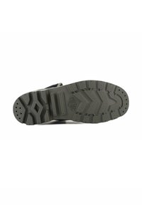 Suola in gomma grigia con un motivo di battistrada testurizzato, caratterizzato da scanalature e grip circolari per la trazione, etichettata con "PALLADIUM."