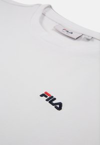 Witte katoenen t-shirt met een ronde hals; heeft een geborduurd Fila-logo in marineblauw en rood aan de linkerkant. Zachte textuur.