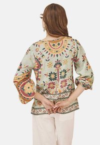 Blusa de estampado floral en verde apagado, con mangas abullonadas, escote redondo y un dobladillo detallado. Fabricada en tejido ligero.