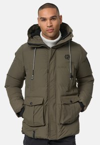 Doudoune vert olive avec capuche, dotée d'une fermeture éclair à l'avant, de deux grandes poches poitrine et d'un patch logo sur le côté gauche. Tissu texturé.