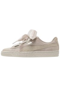 Zapatilla de ante gris claro con lengüeta acolchada y cordones de cinta de satén. Suela texturizada y logo icónico impreso en el lateral. Diseño de punta redonda.
