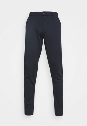 Pantalones azul marino de tejido suave, con cierre de botón, cinturilla con pasadores y piernas ajustadas. Sin patrones ni acentos visibles.