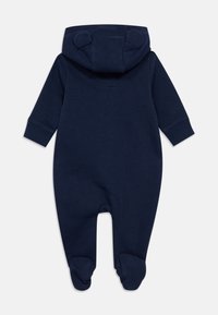 Βαμβακερό φορμάκι σε ναυτικό μπλε με κουκούλα που έχει αυτιά αρκούδας, μακριά μανίκια, καλυμμένα πέλματα και μανσέτες στους καρπούς και τους αστραγάλους.