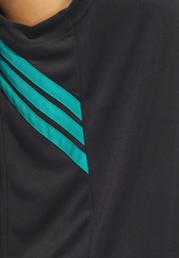 Tessuto nero con tre strisce teal che corrono diagonalmente dalla spalla, texture liscia, design aderente e una leggera lucentezza.