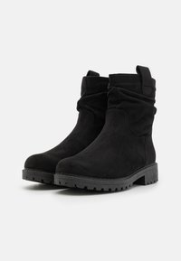 Bottes de cheville en faux-suède noir avec un design froncé, bout rond et semelle en caoutchouc texturé. Comprend une languette à l'arrière pour un enfilage facile.