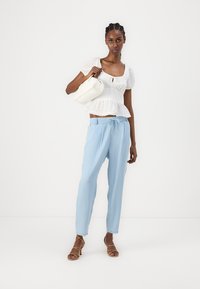 Valge tekstuuriga topp peplum äärega, helesinised püksid paelaga ja pruunid rihmadega sandaldid. Väike valge käekott täiendab välimust.